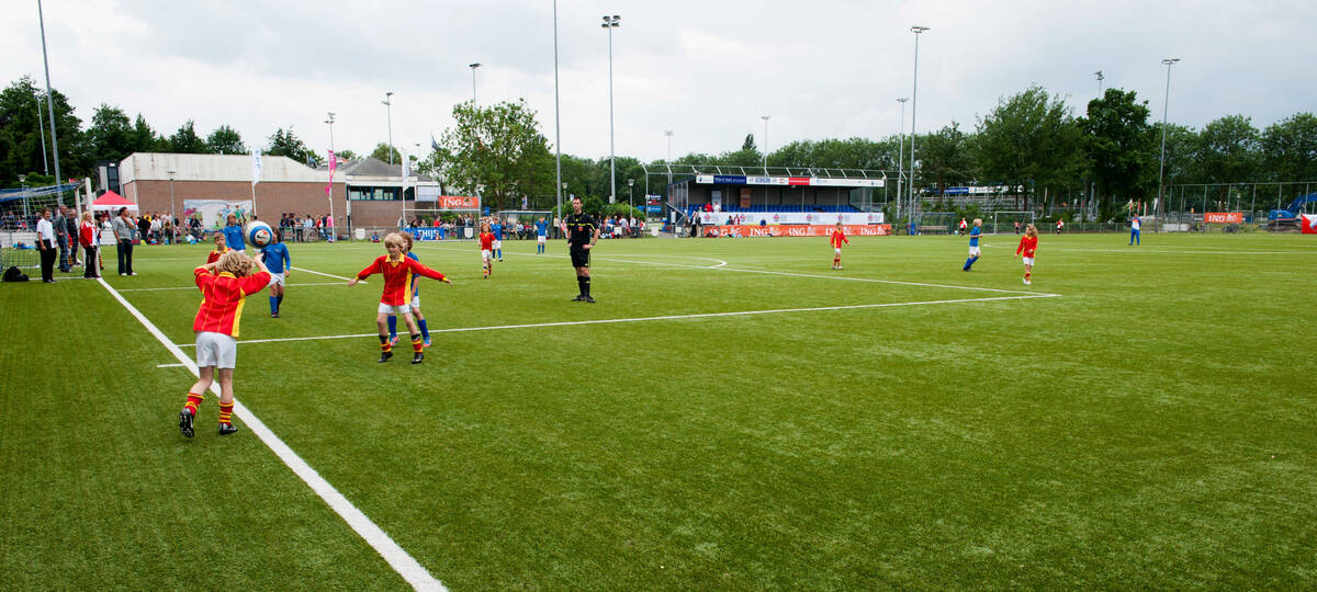 kinderen op het voetbalveld, een jongetje gooit in vanaf de achterlijn