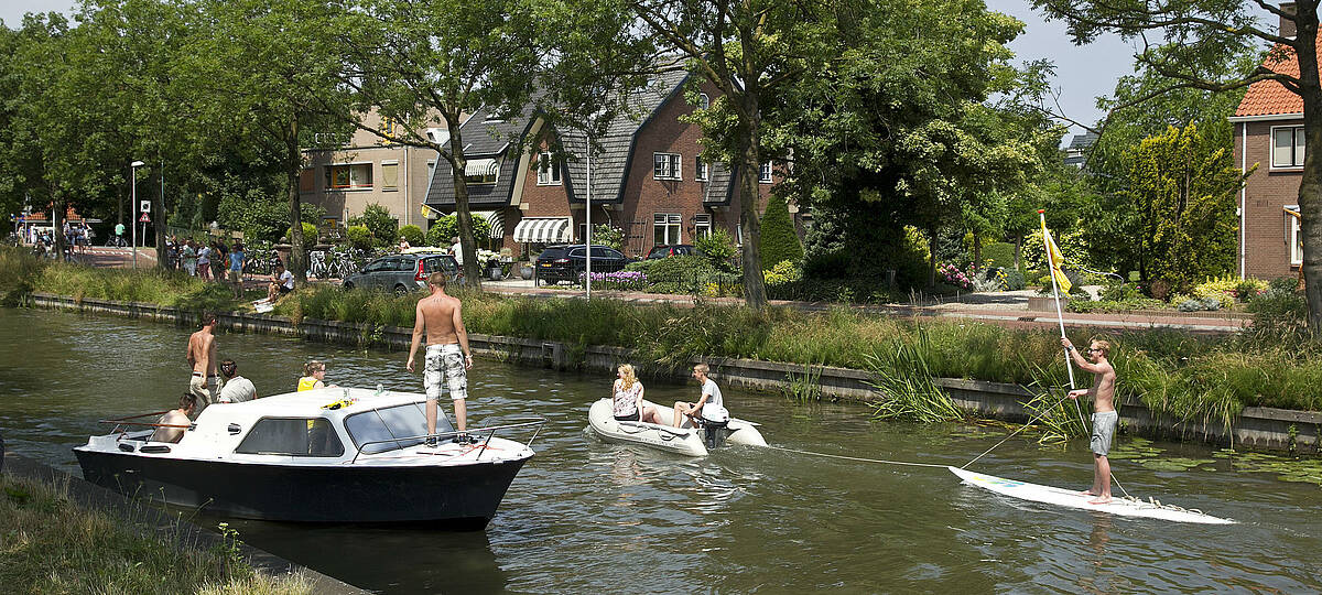 jongens en meisjes varen met bootjes en een surfplank over de Leidsche Rijn