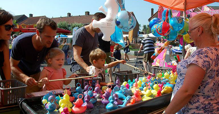kinderen vissen naar plastic eendjes bij een spelletjeskraam op een feestelijke markt